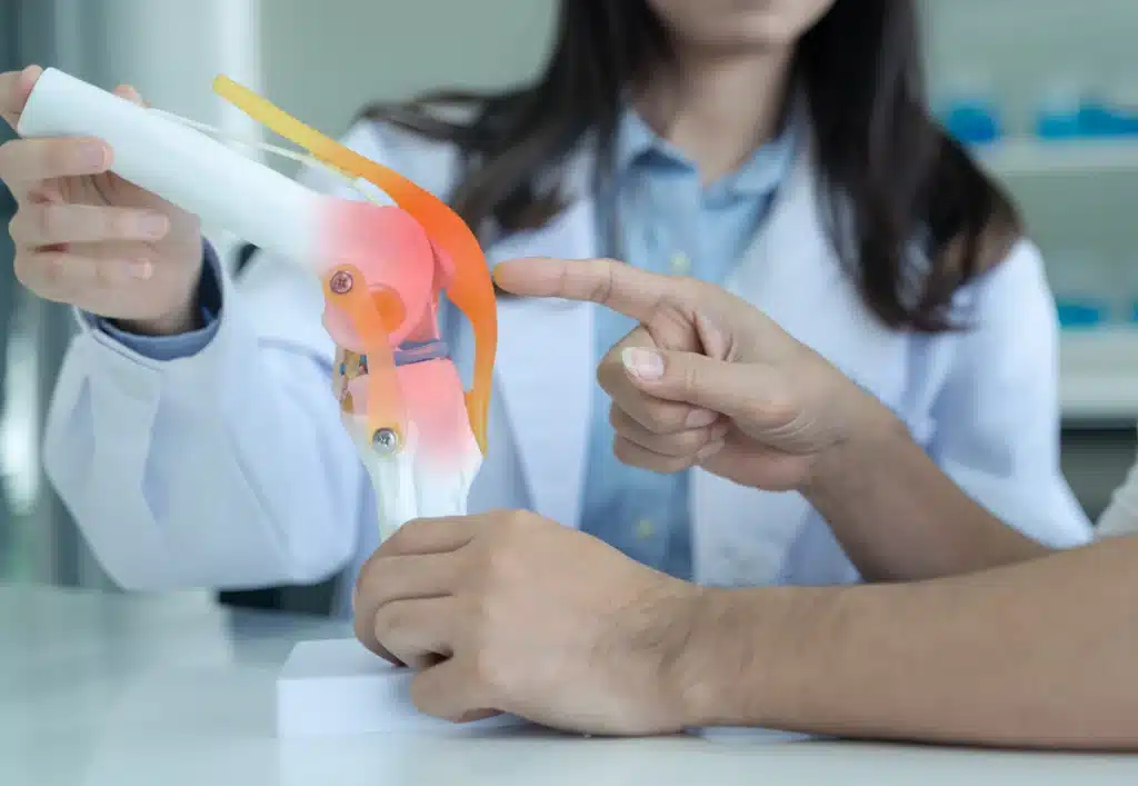 A doctor uses a knee joint model to explain implant positioning as part of a robotic knee replacement