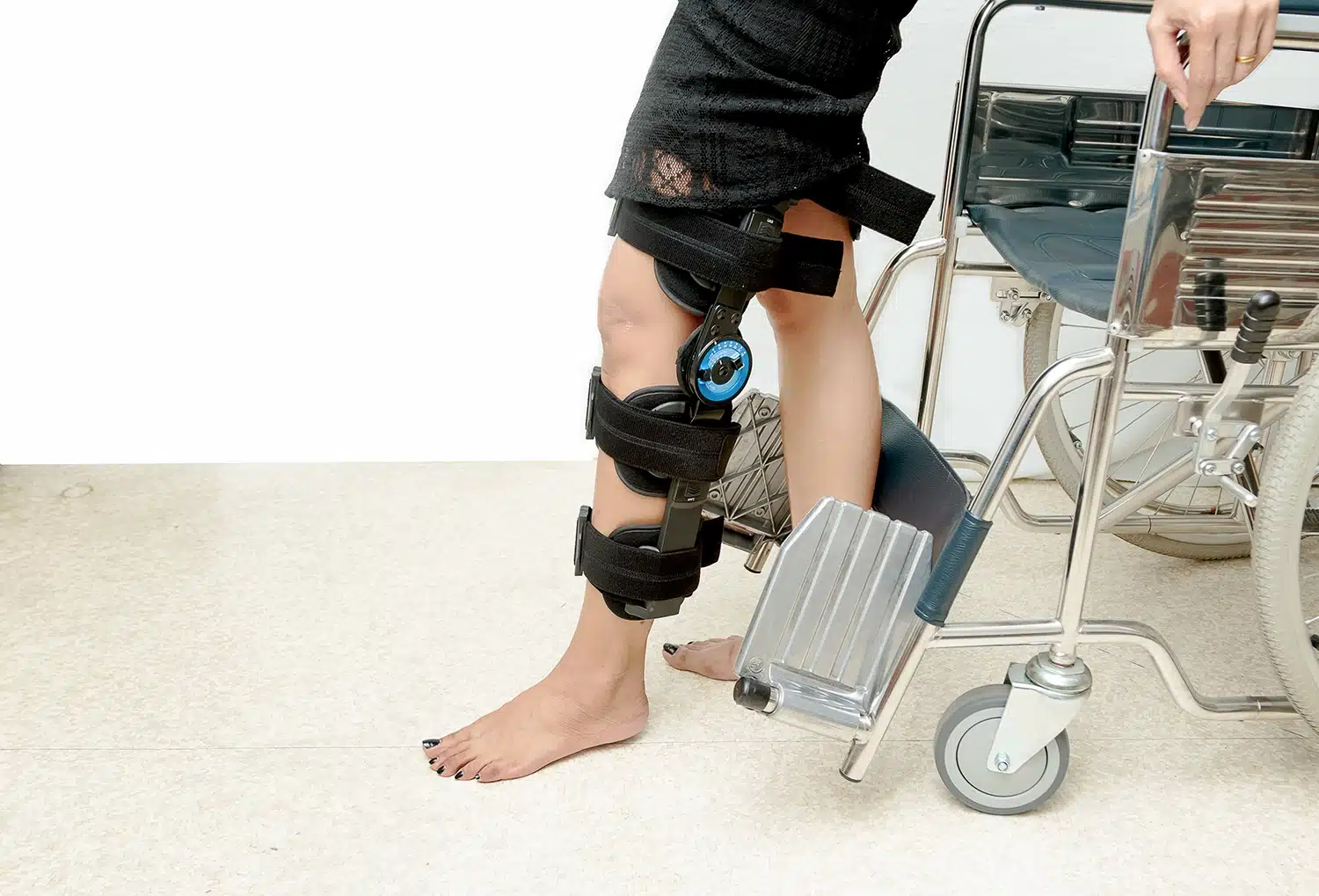A patient wearing a knee brace steps away from a wheelchair, part of early rehabilitation while an ACL graft heals into the bon
